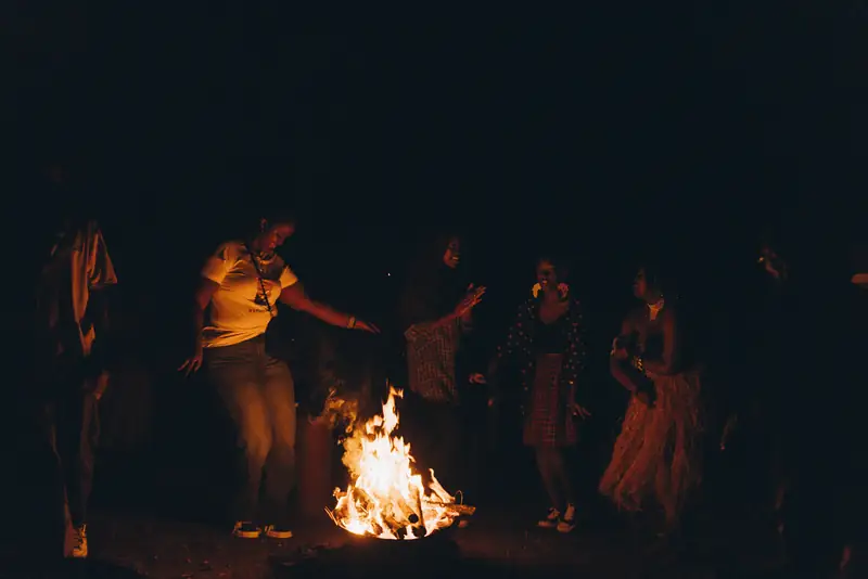 Des participants dansent autour d'un feu, la nuit