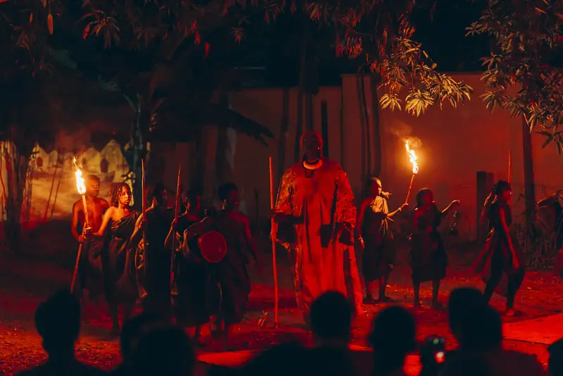 Une guerrière en robe rouge entourée de porteurs de torches