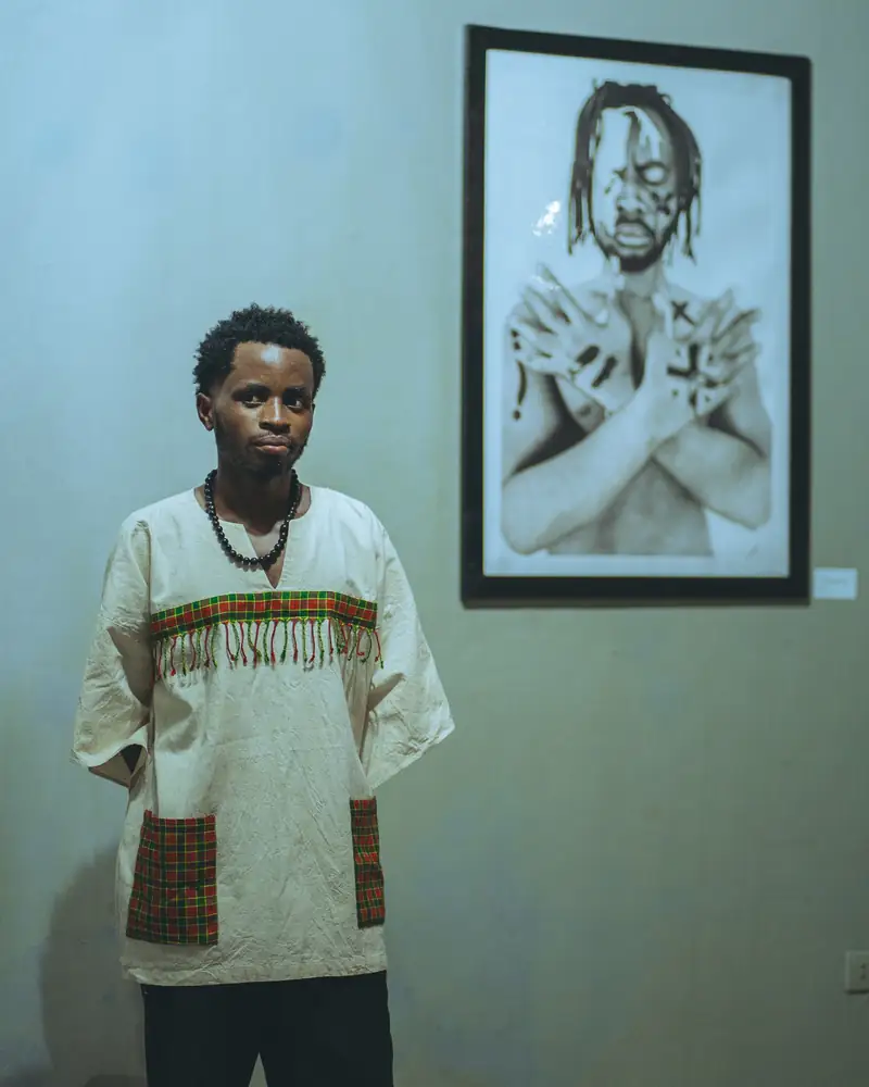 Un jeune homme pose à côté d'un dessin encadré