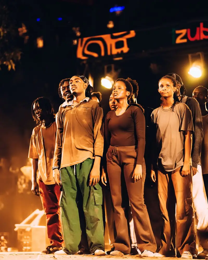 Sept comédiens alignés face au public, éclairage orangé