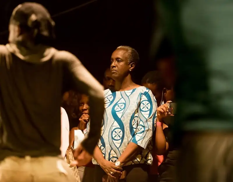 Lydia Nsekera, standing in the audience, watches a dancer