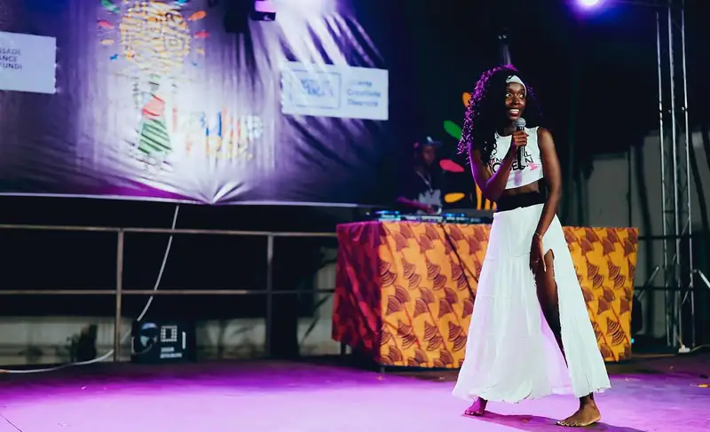 Une chanteuse en robe blanche sur la scène éclairée en violet