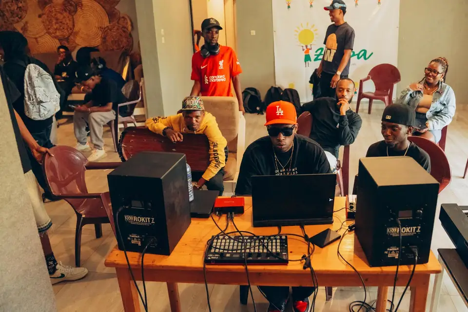 KDaGreat, red cap, at the controls during a session, artists around him